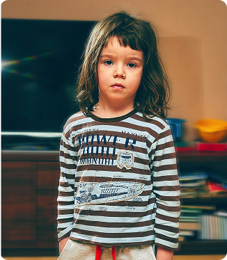 Niña pequeña de pie con expresión seria, vistiendo camiseta de rayas blancas y negras, en un entorno escolar. Niña pequeña de pie con expresión seria, vistiendo camiseta de rayas blancas y negras, en un entorno escolar.