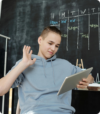 Adolescente sentado frente a un pizarrón con fórmulas matemáticas, sonriendo mientras usa una tableta digital. Adolescente sentado frente a un pizarrón con fórmulas matemáticas, sonriendo mientras usa una tableta digital.